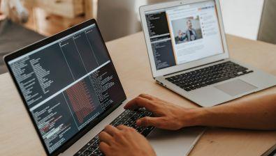 Mains d'un homme qui tape du code informatique sur un ordinateur portable